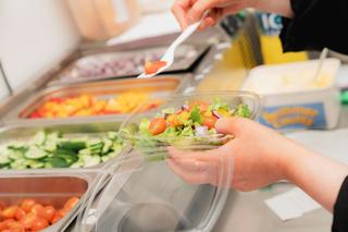 Close up of a hospitality learner putting together a salad in a Novus kitchen