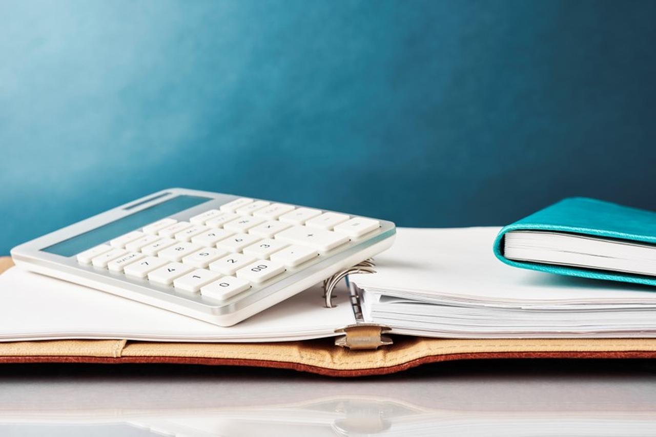 A folder opened on top of a table with a notebook and calculator sitting on top of the folder
