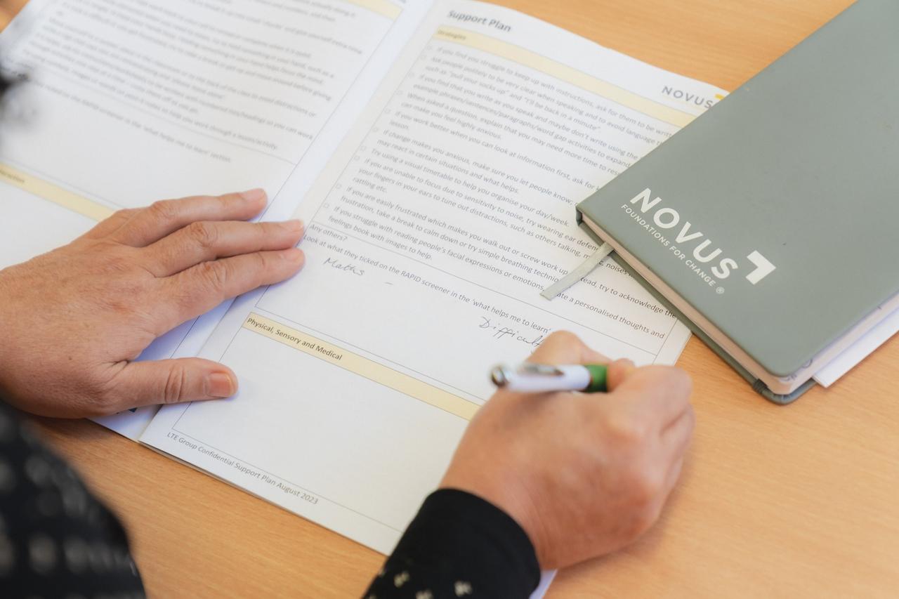 Behind the shoulder shot of a Novus colleague filling out a Novus education induction form