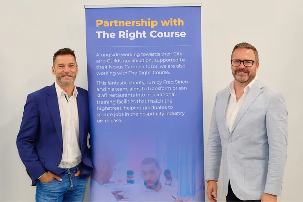 Two people smiling next to a Novus employer partners promotional banner.