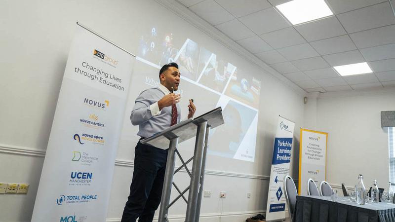 Speaker presenting at a Novus event on education‑led rehabilitation and training pathways