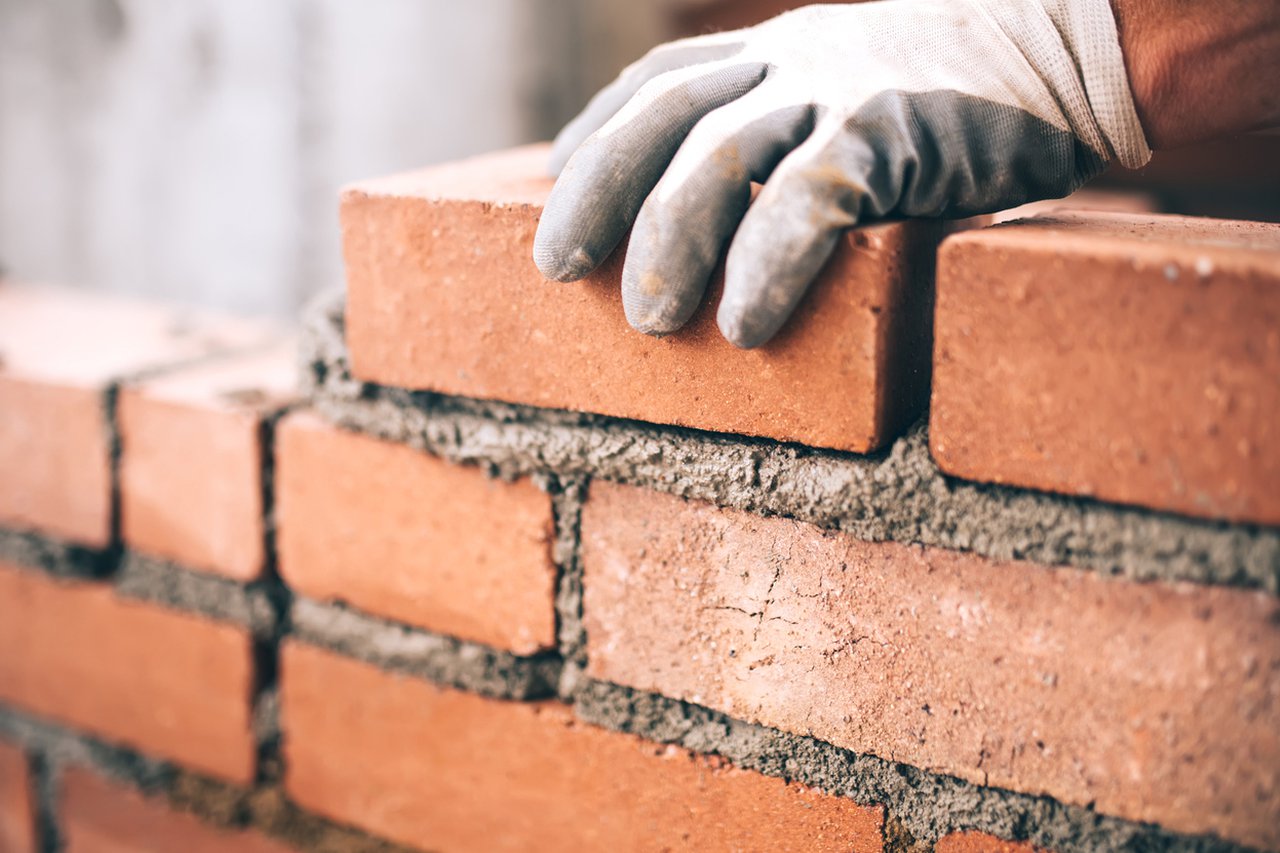 Apprentice hand building a wall