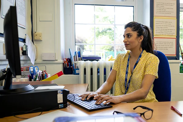 Person typing on a computer in an office, representing the role of a Hub/Curriculum Manager in prison education.