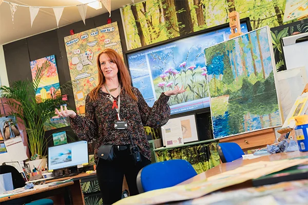 A teacher at the front of a class leading a session