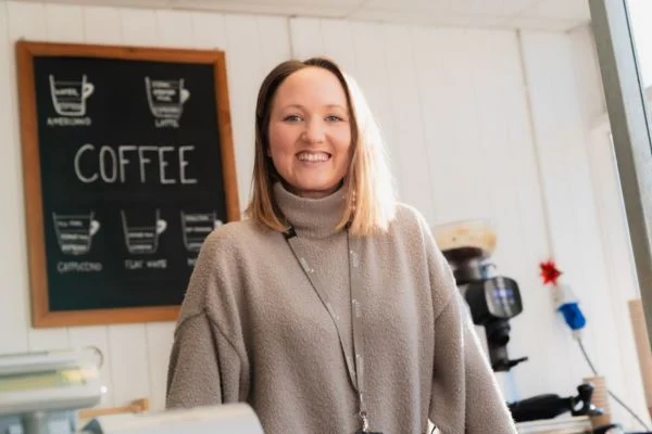 Novus teacher smiling, coffee infographic on the wall