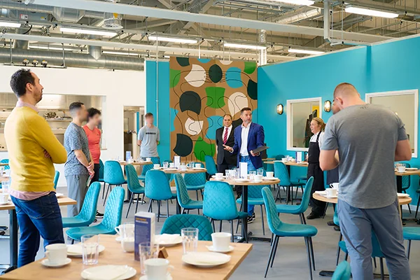 Group of people in a modern, colorful dining and learning space, illustrating the collaborative and innovative environment of a unique curriculum.