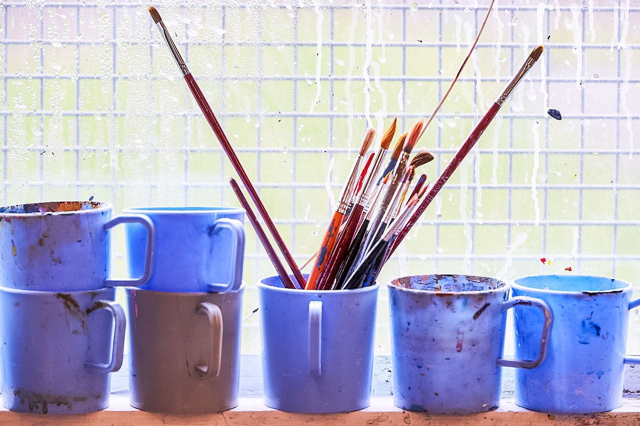 A row of blue cermaics with paint brushes in them