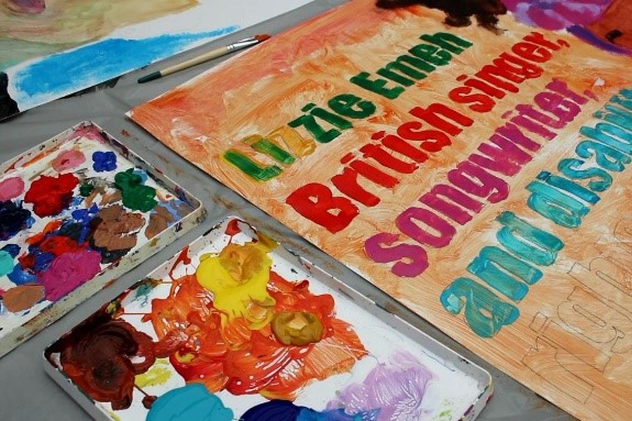 A painting that is being worked on, with different paints on the floor next to it.