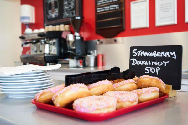 Tray of strawberry donuts priced at 50p each in a cafe