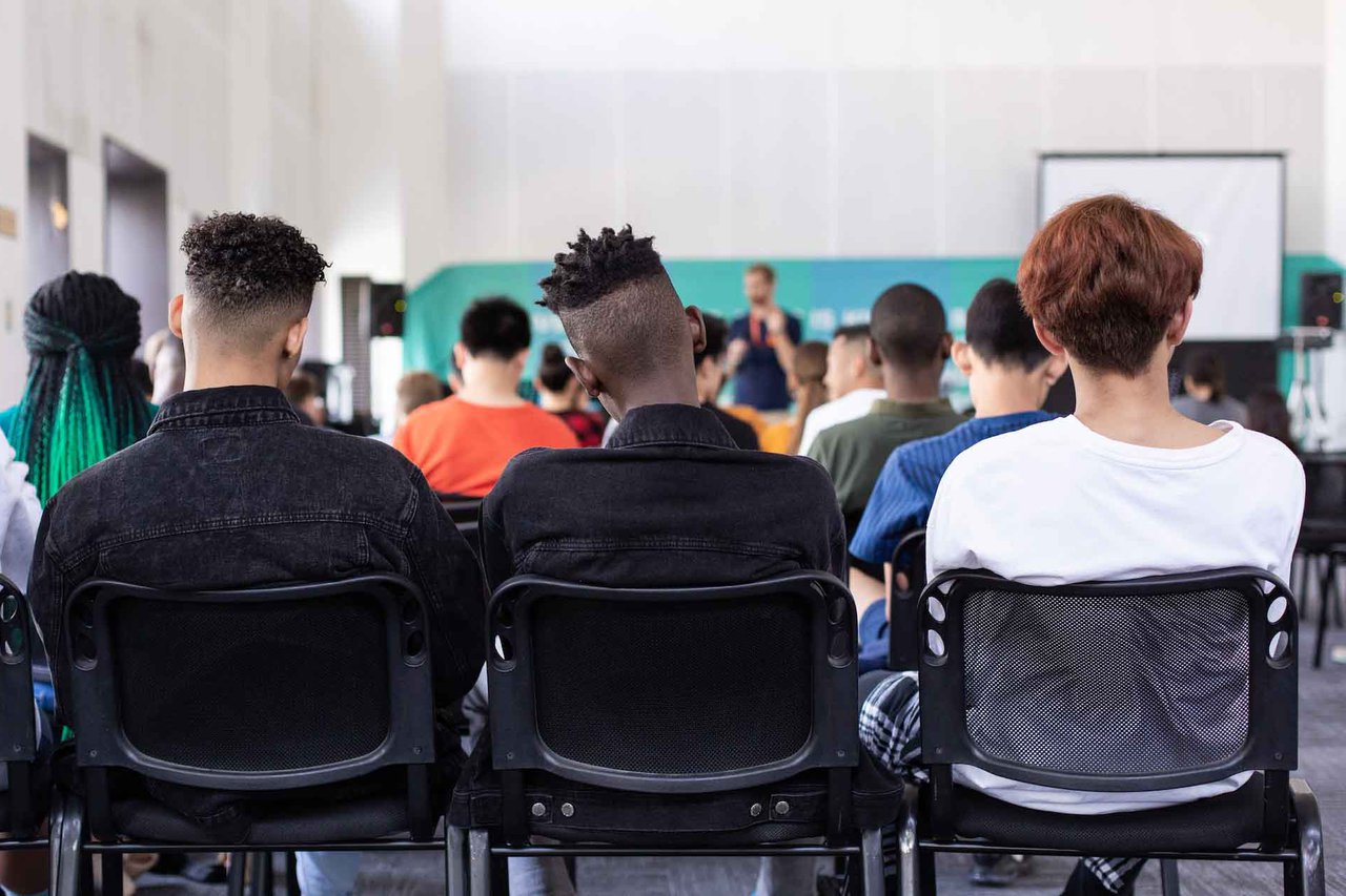 Three people watch a lecture