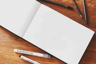 A blank page with art supplies lying near