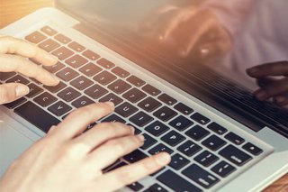 Close-up of someone typing on a laptop