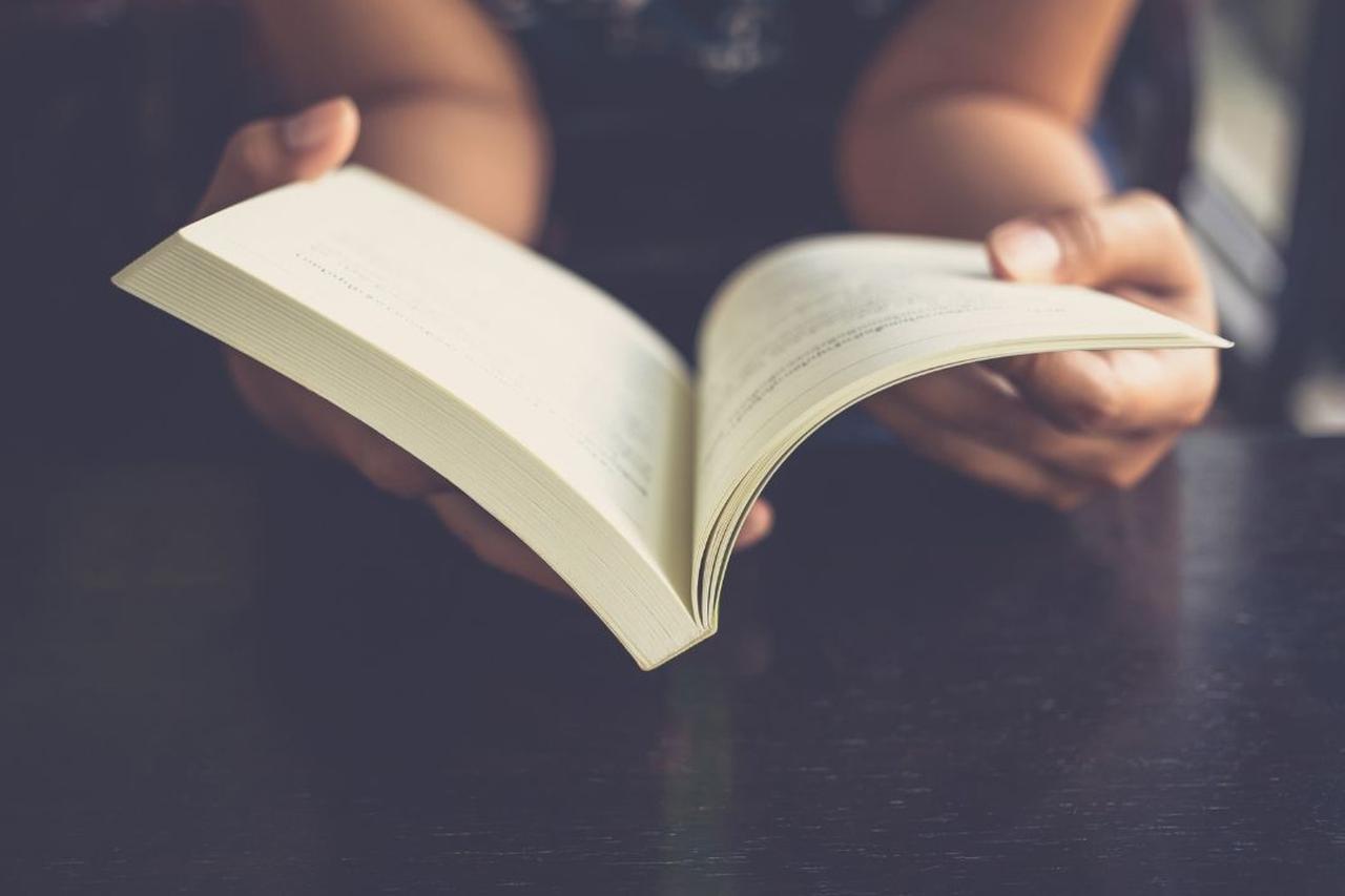 Close-up of a person holding and reading an open book.