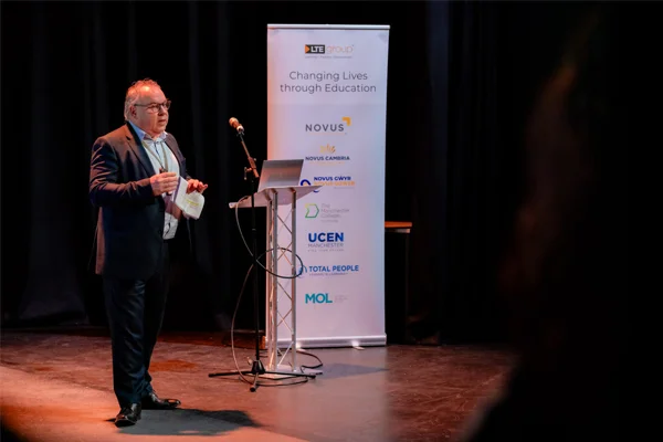 Managing Director Peter Cox delivers a keynote presentation on stage next to an LTE Group banner reading "Changing Lives through Education".
