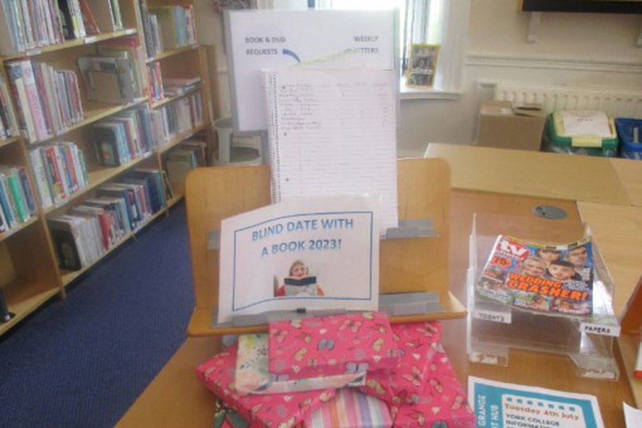 Books wrapped in wrapping paper stacked on a table with a sign displaying the text 'Blind-date with a book'