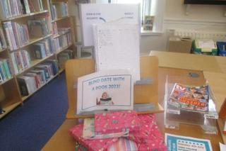 Books wrapped in wrapping paper stacked on a table with a sign displaying the text 'Blind-date with a book'
