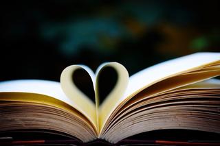 An open book with a couple of the pages folder over in the shape of a heart