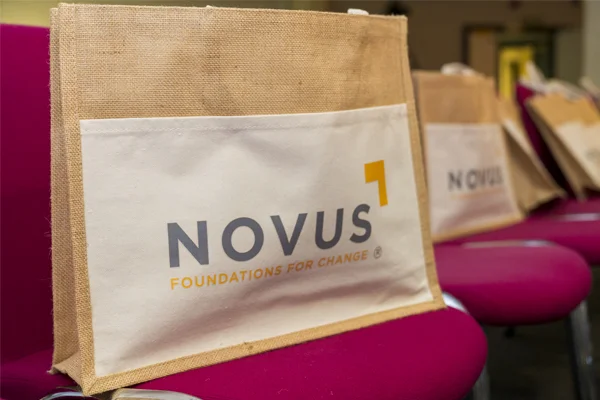 Close-up of a Novus branded bag placed on a conference chair, representing the organisation’s story and identity.