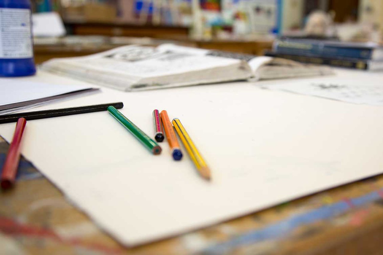 A workdesk covered in papers and pens