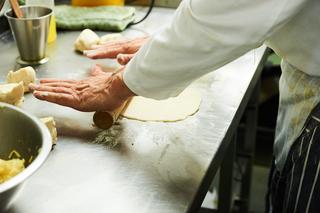 A chef flattening some dough