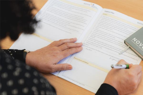 Novus tutor marking work from an adult learner as part of prison education and skills development.