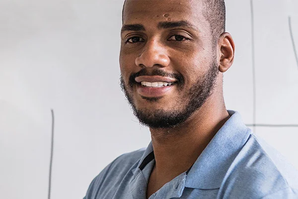 Close-up of a smiling Novus higher education tutor in a classroom setting.