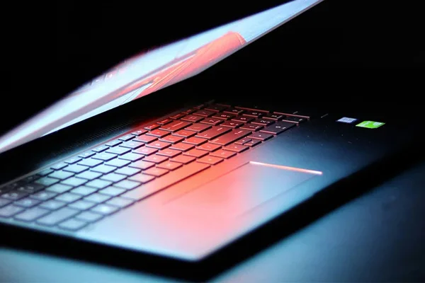 A partially closed laptop, with a colour screen contrasting against a black background