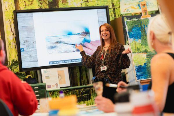 Novus teacher pointing at a big screen whilst teaching a class