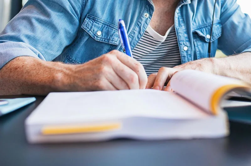 A man writing in his notebooks