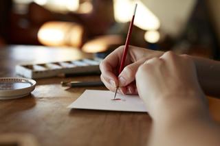 Close up of a person painting on a piece of blank paper