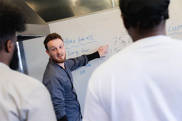 A teacher talking and pointing at a white board