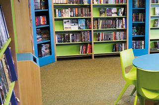 Interior view of a vibrant Novus learning space with colourful chairs, tables, bookshelves, and computers, designed to support education and study.