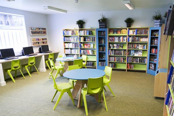 Interior view of a vibrant Novus learning space with colourful chairs, tables, bookshelves, and computers, designed to support adult education and study.