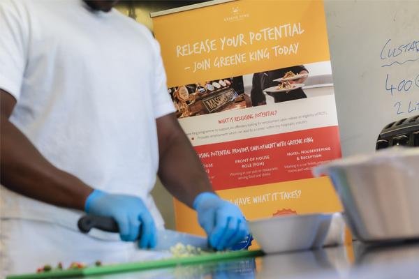 Close-up of a Novus adult learner chopping food in a kitchen skills class.
