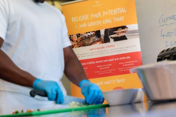 Learner chopping food in cooking class wearing blue plastic gloves