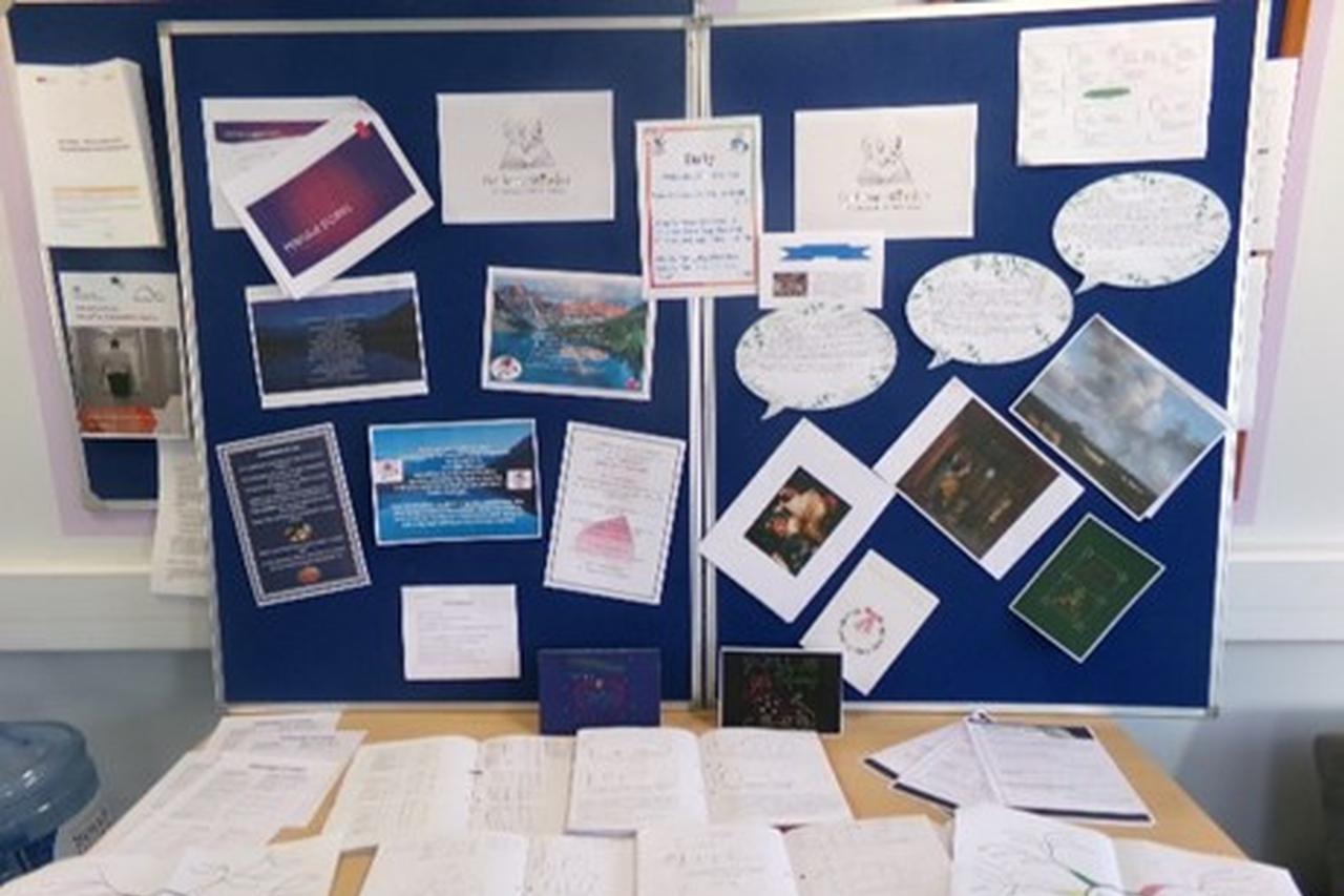 A desk and navy blue display board filled with pictures and written notes