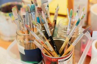 An assortment of paintbrushes in paint pots on a table