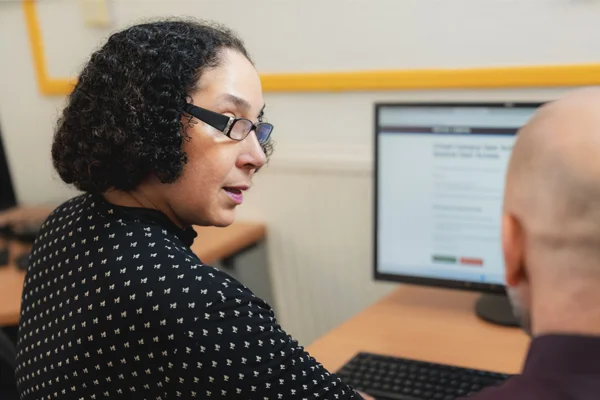 Novus tutor providing one-to-one support to an adult learner in a classroom setting.