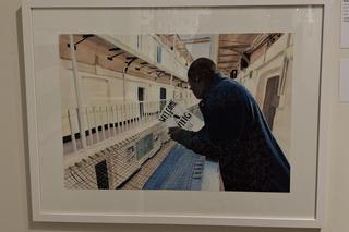 Painting of a man in prison looking over a wing