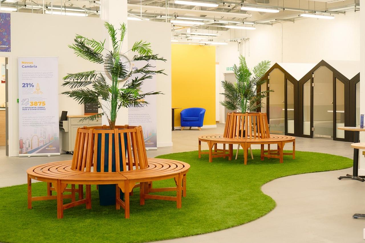 Bright wellbeing hub at HMP Berwyn with indoor planting, circular seating areas, private meeting pods and a large open space for wellbeing and support activities.