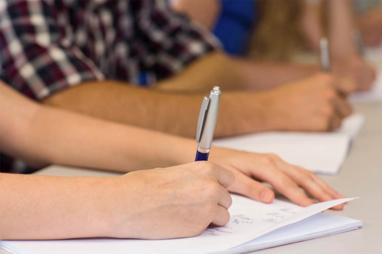 A group of students writing at a desk