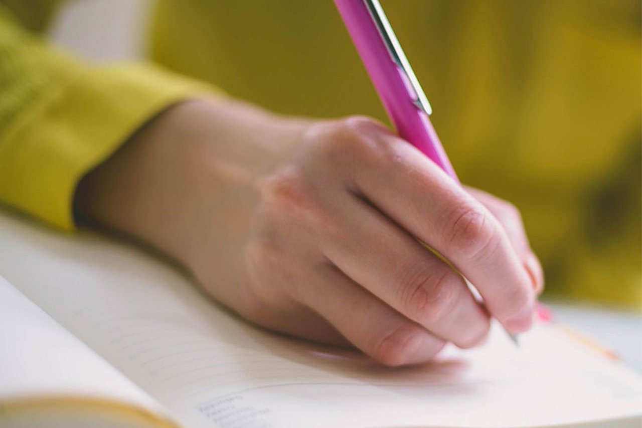 Close-up of someone writing on a pad of paper