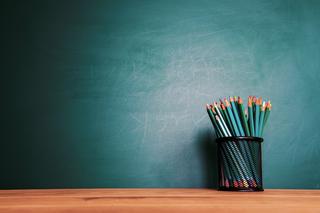 Plain board with colorful pencils in a jar displayed in front of the board