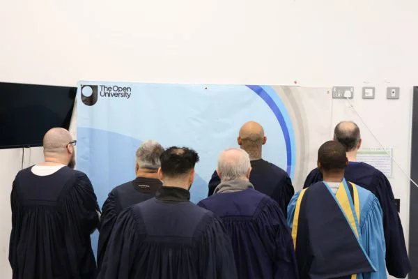 Group of graduates wearing graduation gowns facing away from the camera